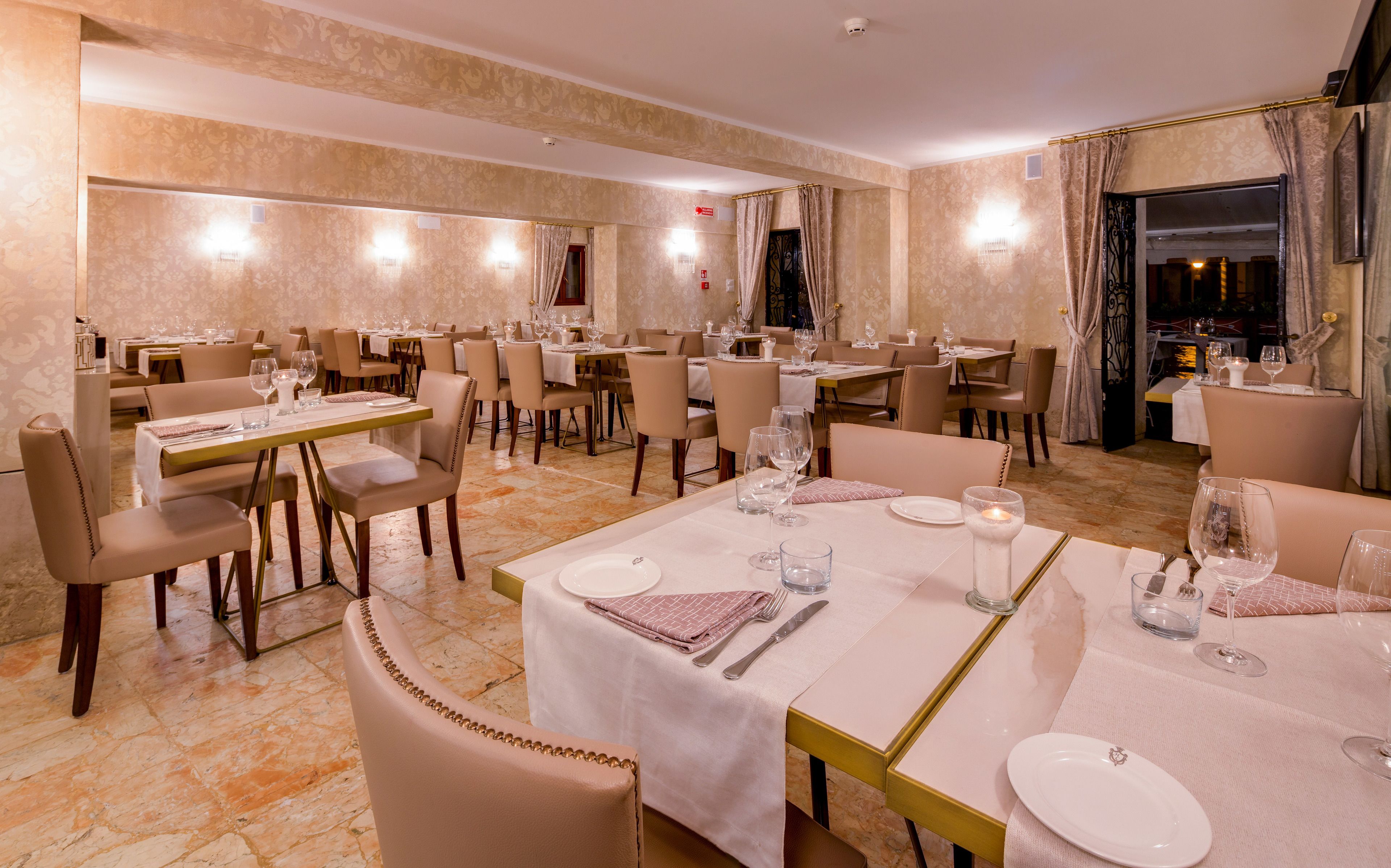 A hotel dining area with multiple tables set for dining, each with chairs and table settings.