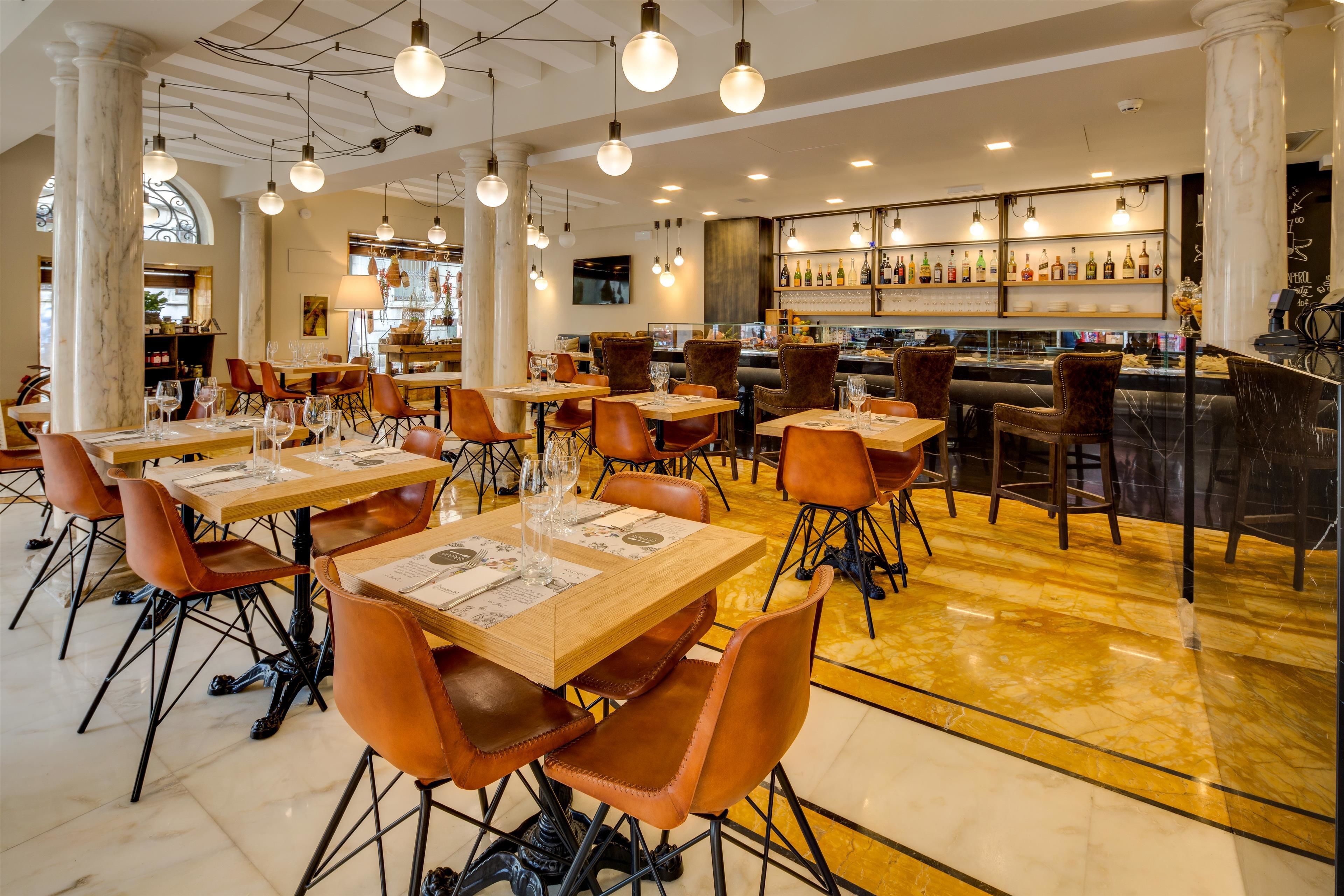 Een restaurant met marmeren vloeren, houten tafels en oranje stoelen.