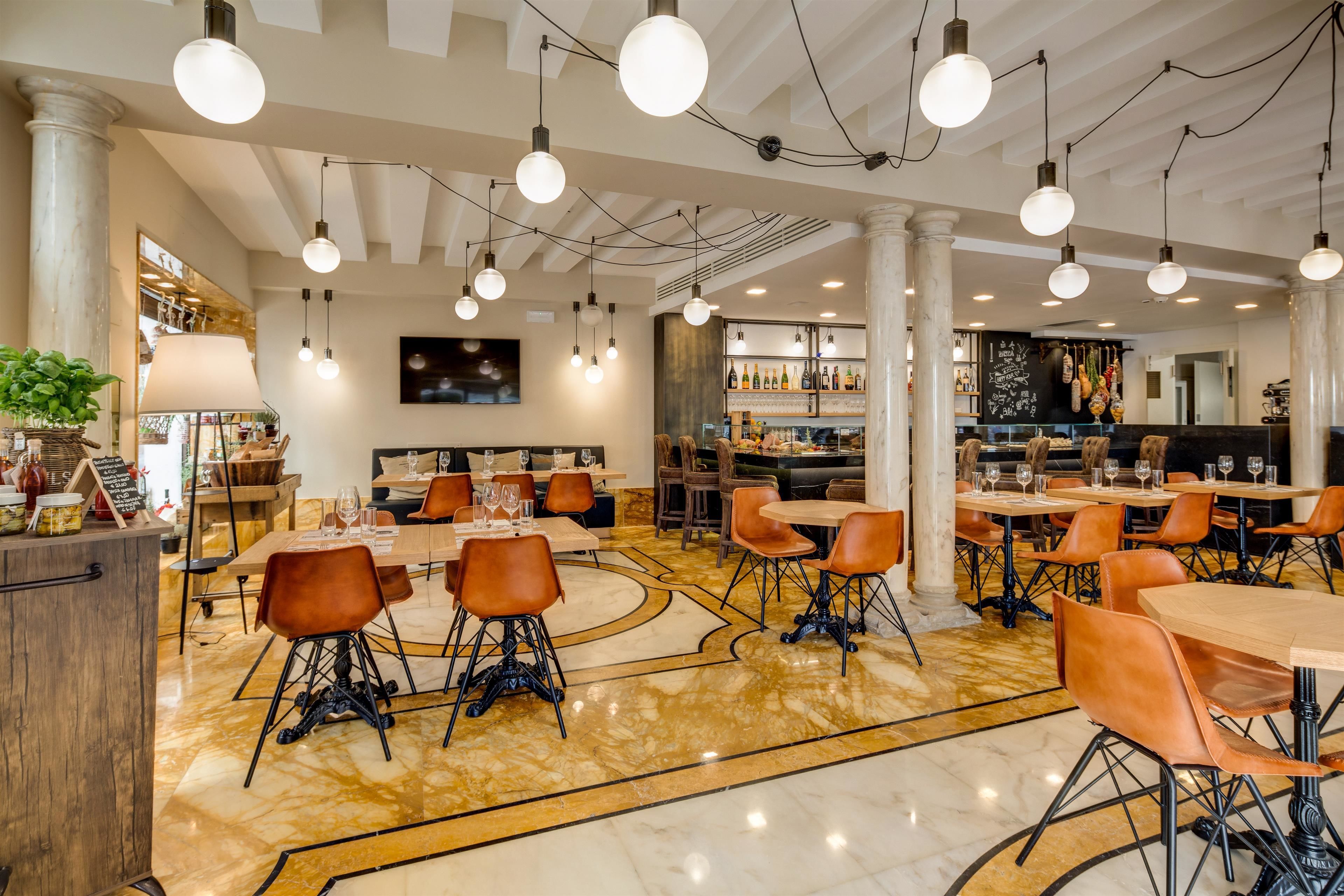 Un restaurant spacieux doté d’un sol en marbre, de tables rondes et de chaises orange.
