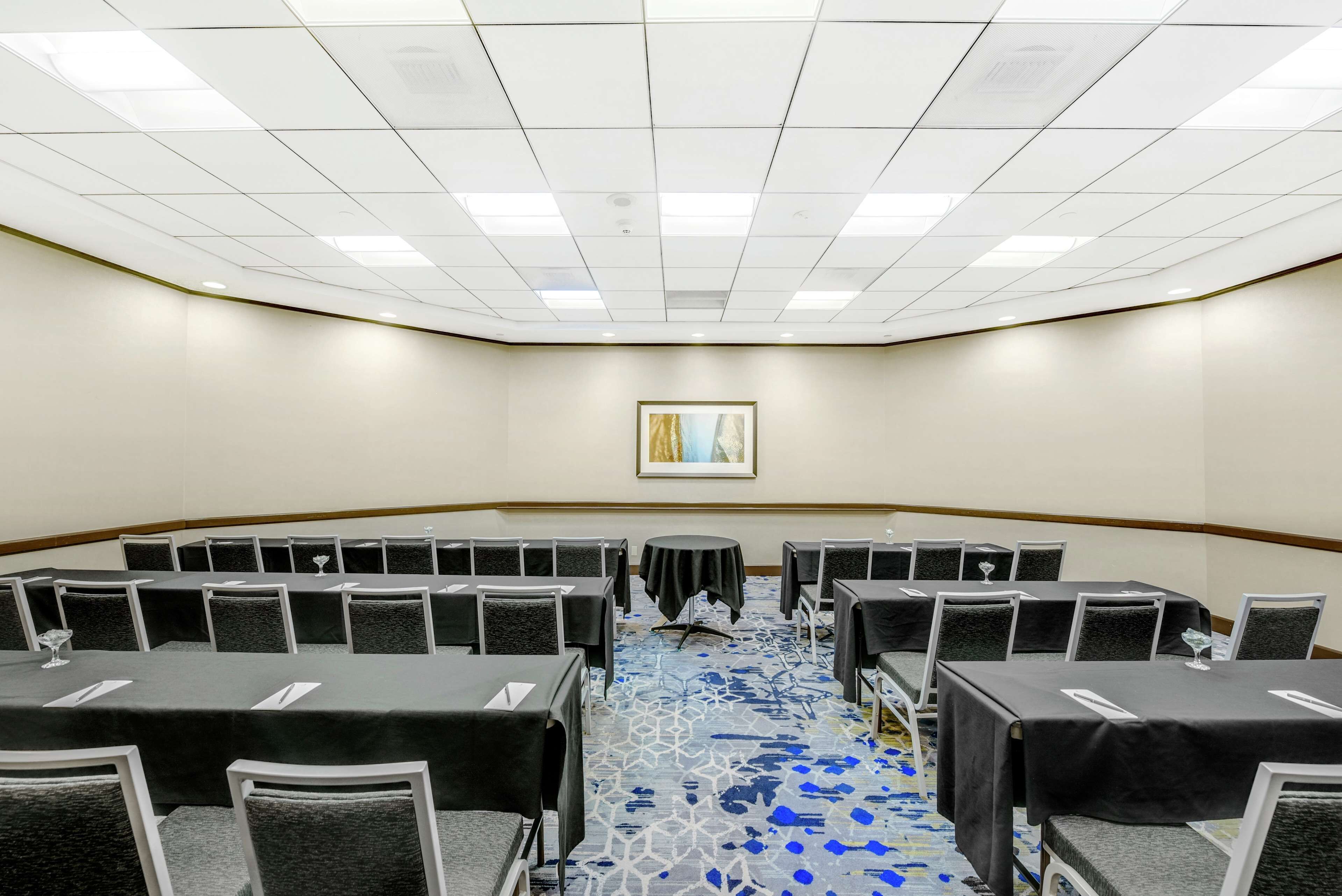 A conference room with a curved layout, multiple tables with black tablecloths, and chairs.