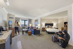 A hotel room with a bed, a sofa, a desk, and a dining area.