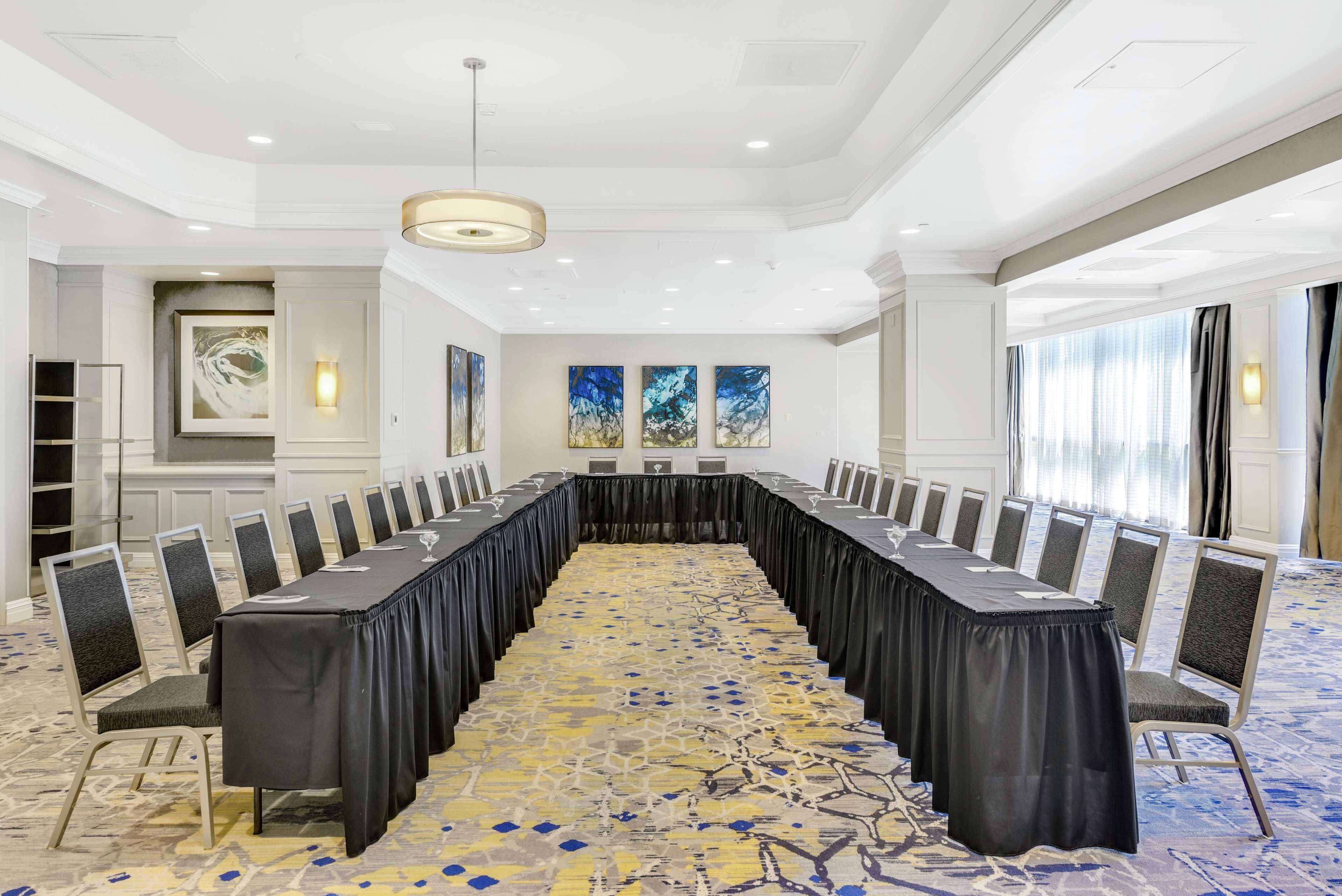 A conference room with a long table, chairs, and artwork on the walls.