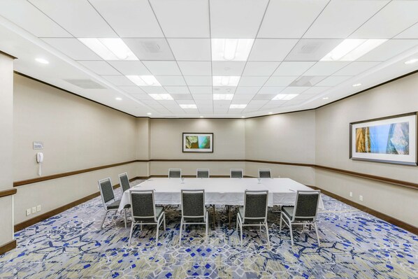A conference room with a long table, chairs, a phone, and artwork on the walls. - Embassy Suites by Hilton Anaheim Orange (Orange)