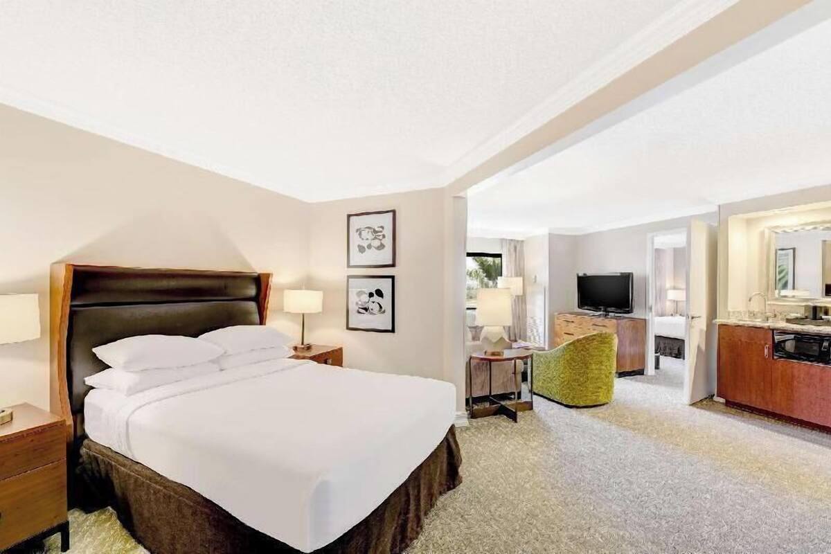 A hotel room with a large bed, a desk, a chair, a television, and a bathroom.