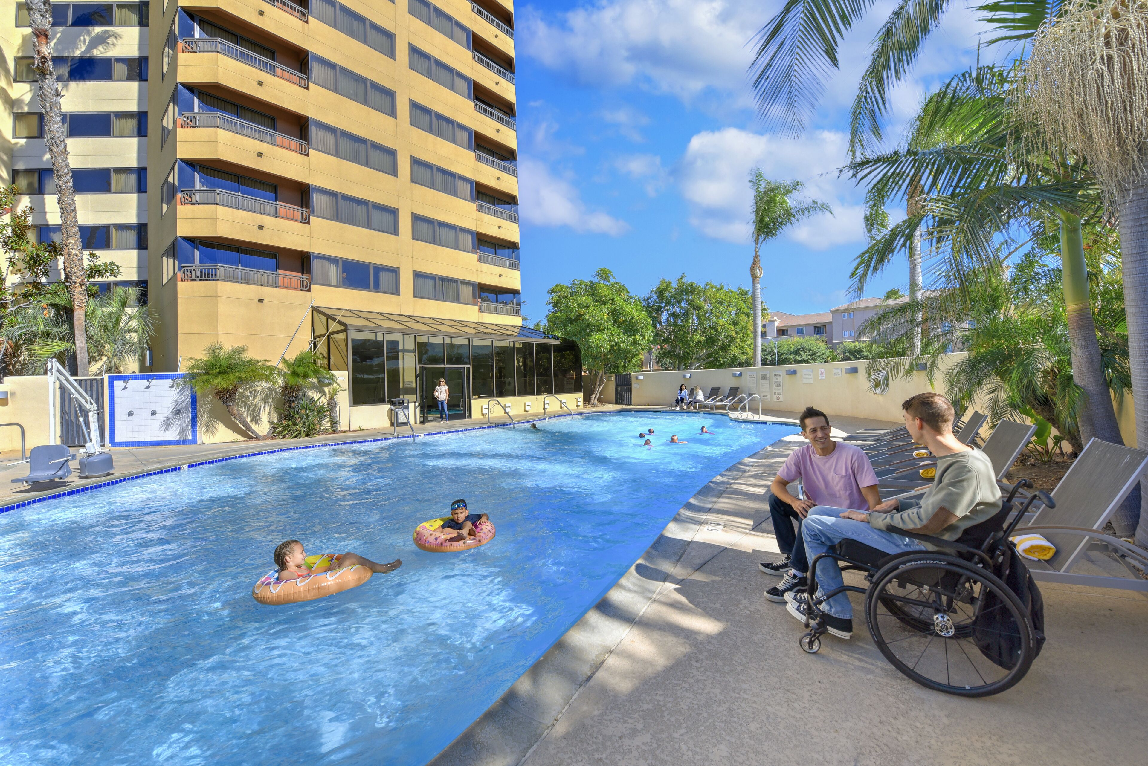 Une piscine avec des personnes dans l’eau et au bord de la piscine.