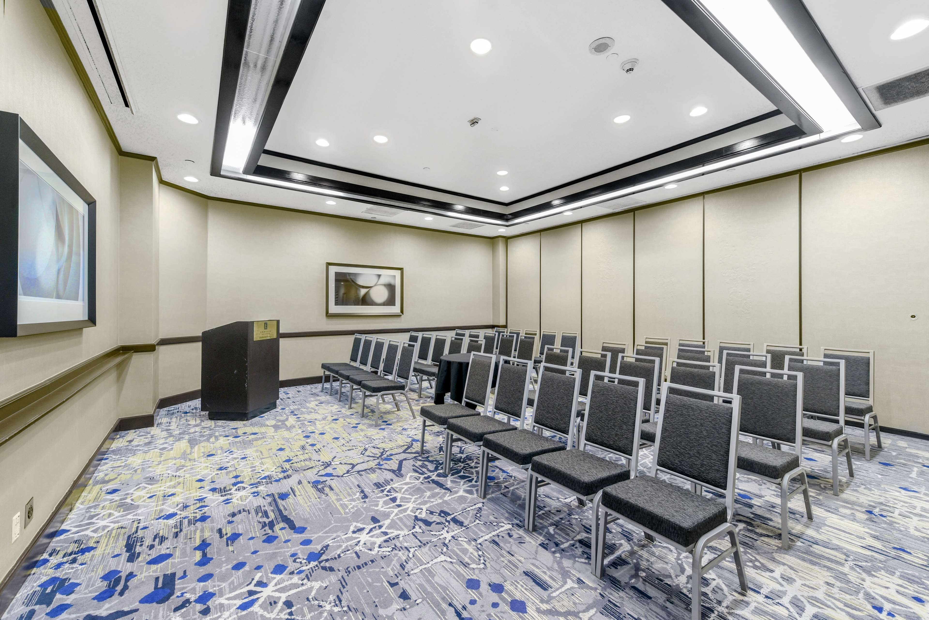 A conference room with rows of chairs, a podium, and a carpeted floor.