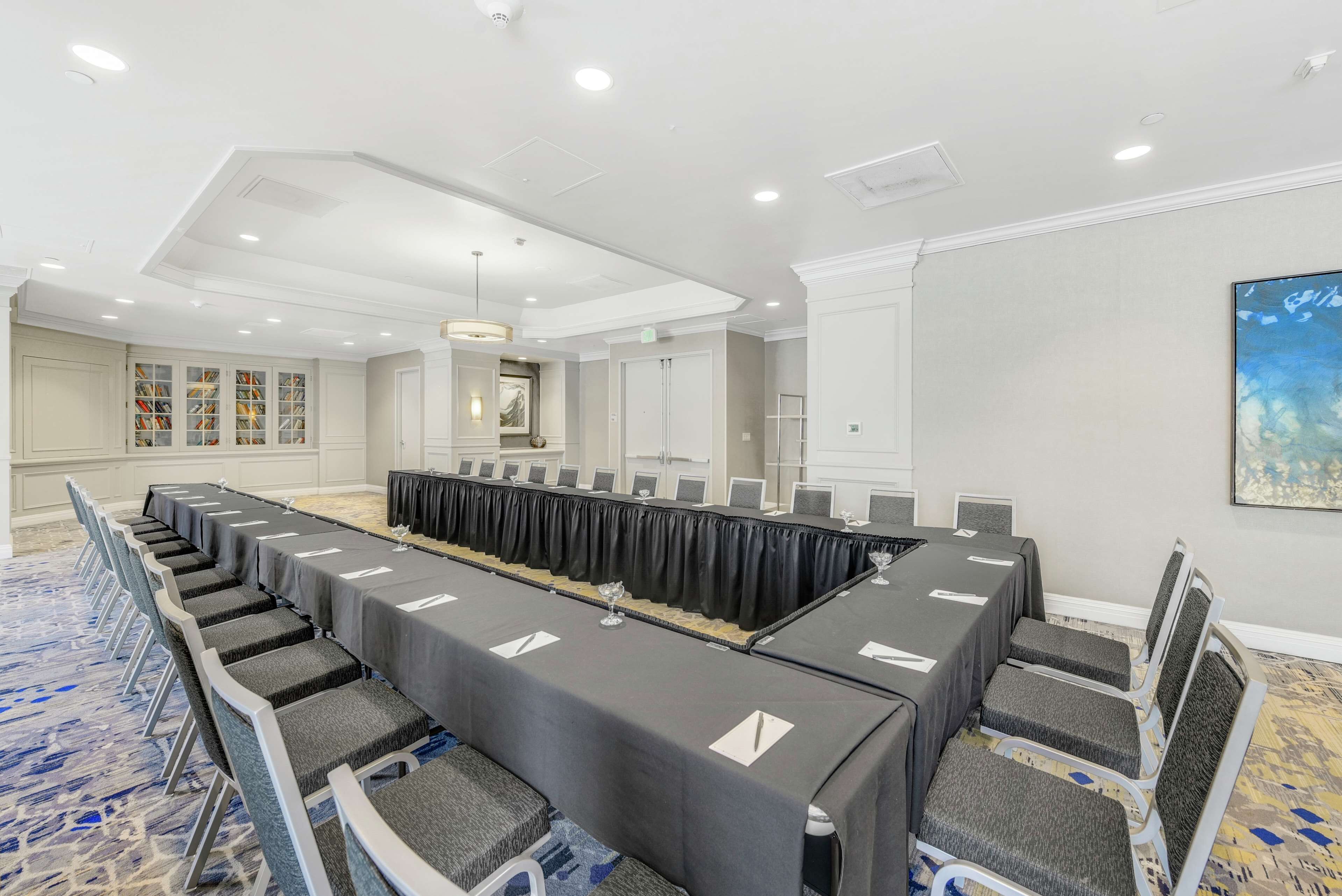 A conference room with a long table, chairs, and a carpeted floor.