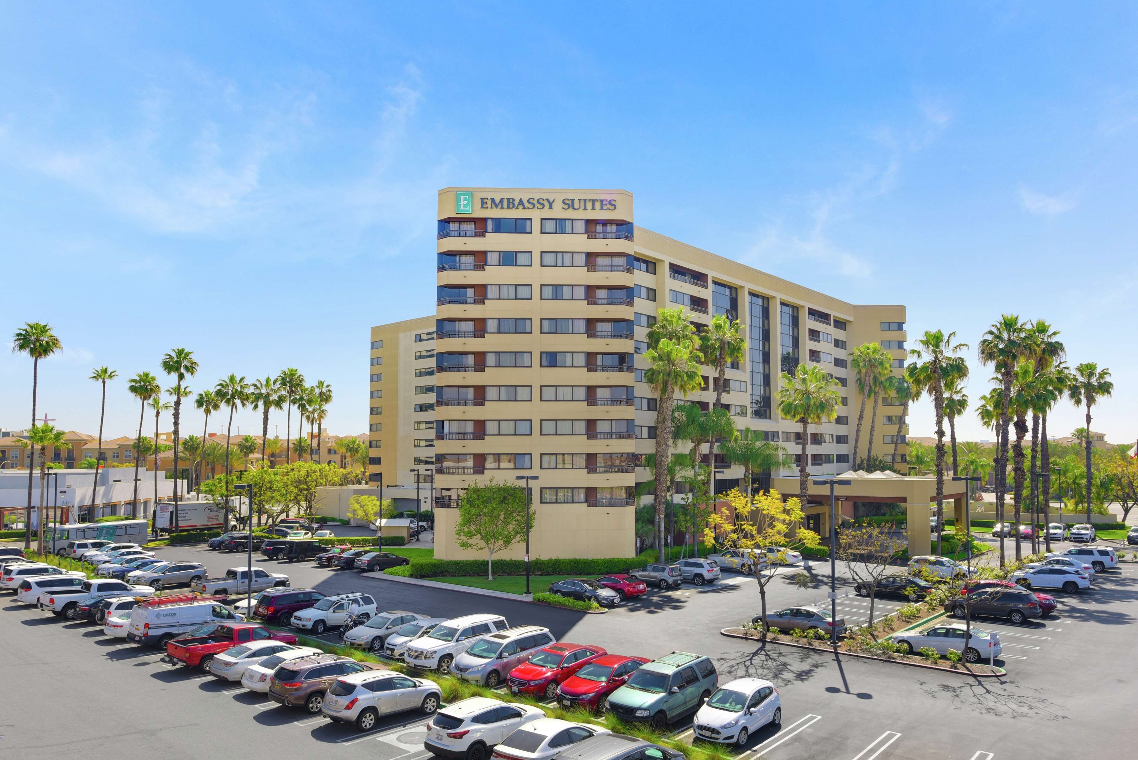 A multi-story building labeled "Embassy Suites" with a parking lot full of cars.