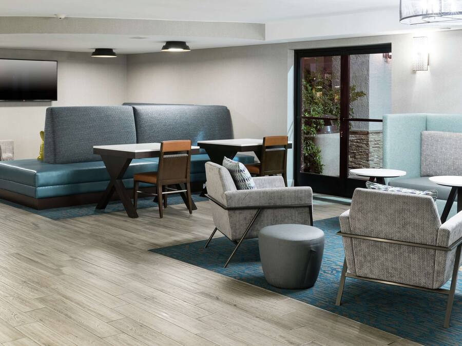 Un moderno espacio lounge con disposición de asientos, un televisor de pantalla plana y vistas al exterior.