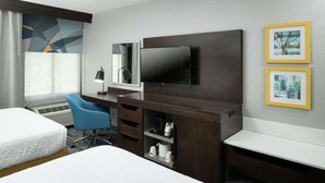 A hotel room with a bed, a desk with a flat-screen TV, a chair, a coffee machine, and a shelf with toiletries. - Hampton Inn Los Angeles/Santa Clarita (Stevenson Ranch)
