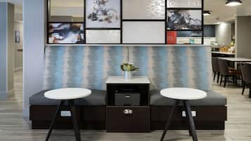 A modern hotel lobby with a seating area featuring two white tables and a sofa.