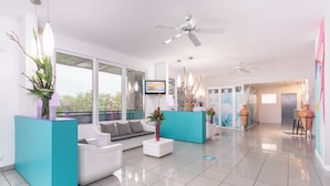 A modern lobby with white sofas, teal accent pieces, and a reception desk. - Karibea Valmenière Hôtel (Fort-de-France)