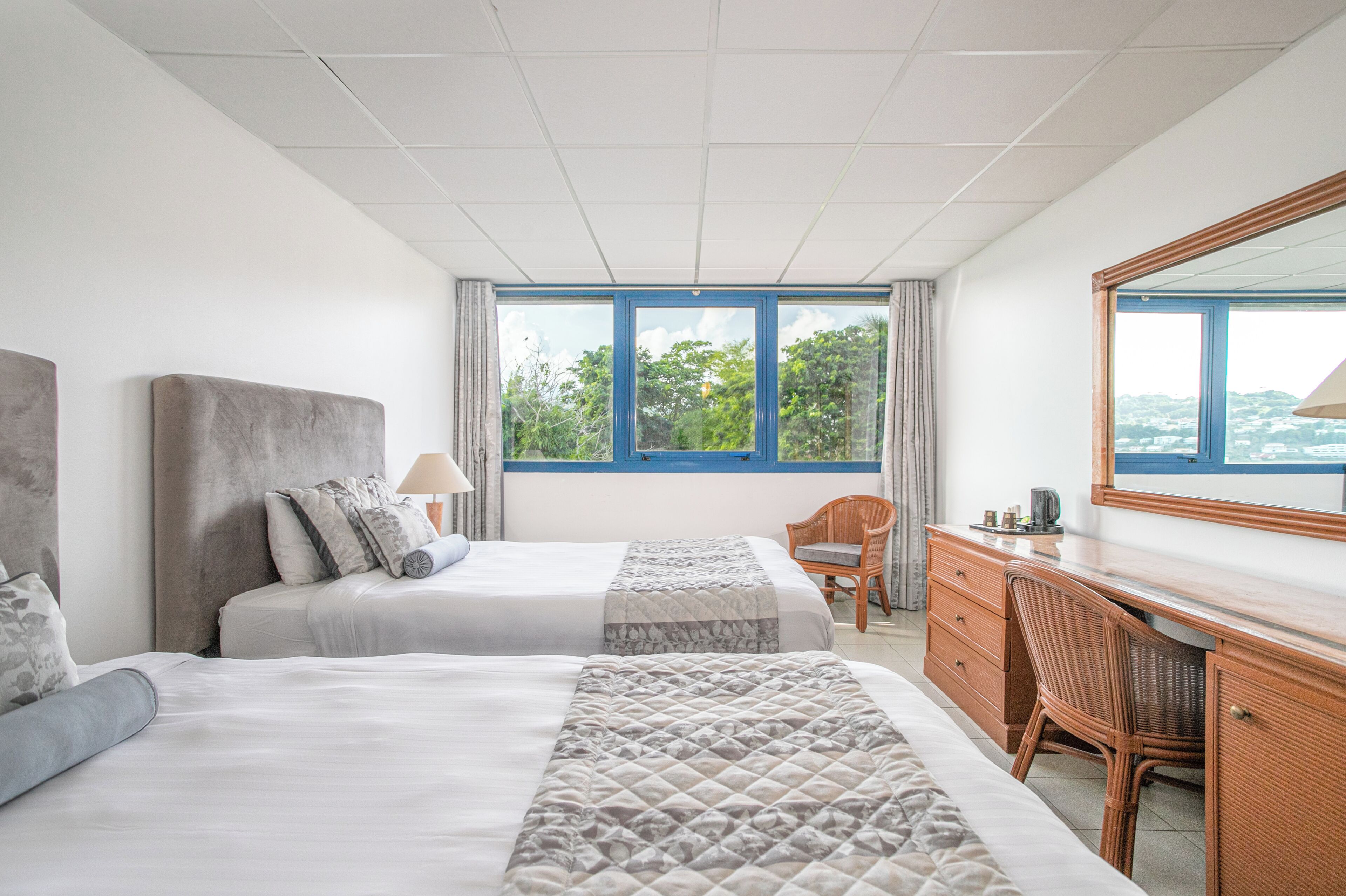 A hotel room with two beds, a desk, and a chair.