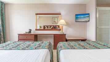 A hotel room with two beds, a desk, a chair, a television, and a window with curtains.