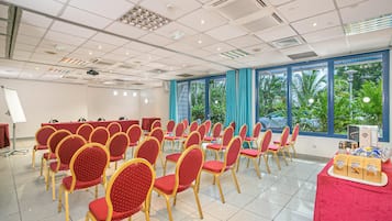 A conference room with rows of red chairs, a projector, and a table with snacks.