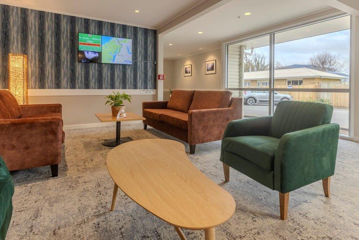 A modern lobby with a large TV screen, comfortable seating, and a view of the outside.