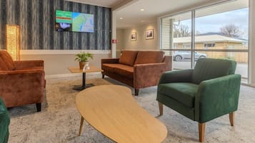 A modern lobby with a large TV screen, comfortable seating, and a view of the outside.