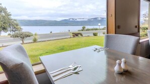 A dining table set with cutlery and salt shakers, overlooking a lake and mountains. - Kingsgate Hotel Te Anau (Te Anau)
