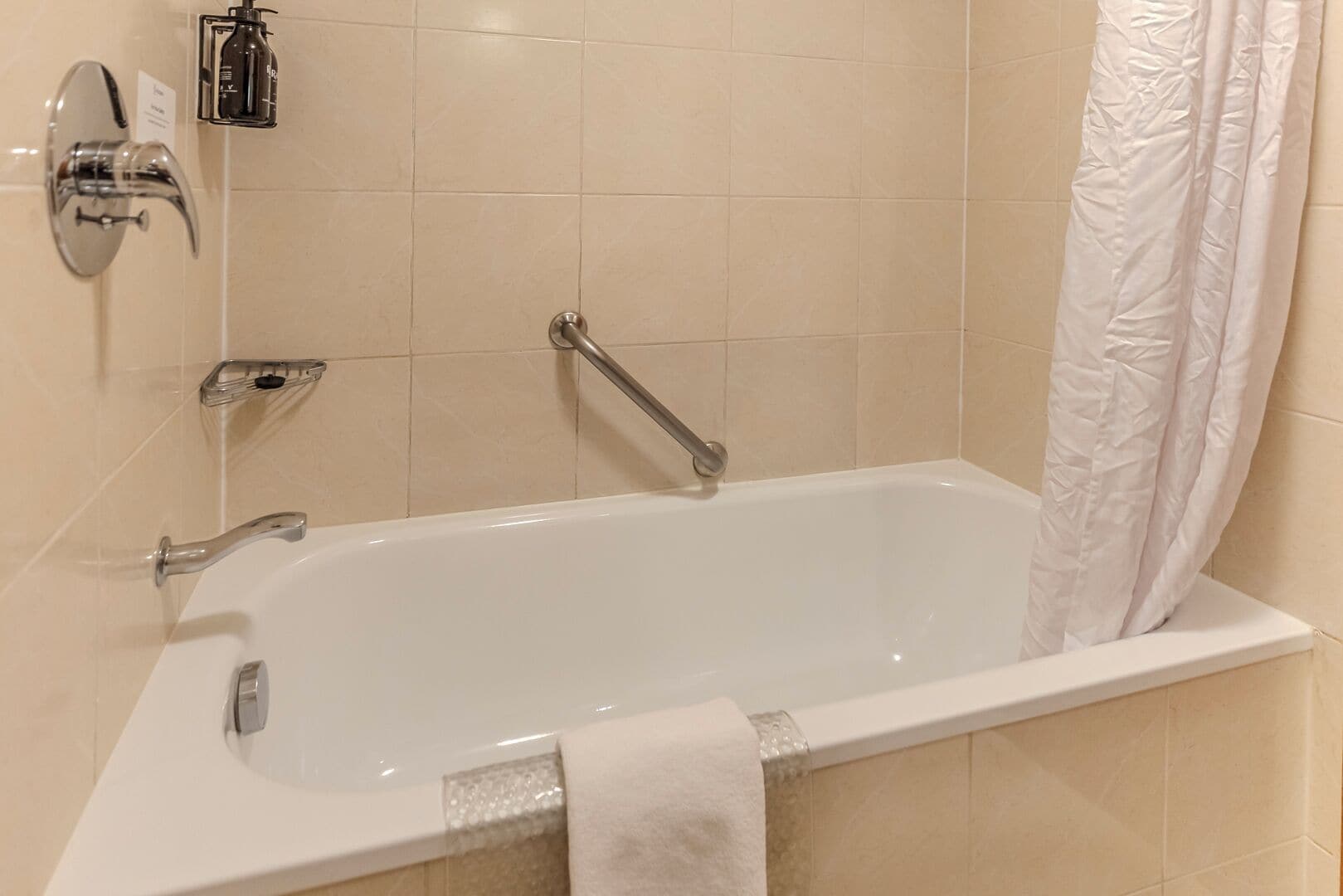 Un baño moderno con una bañera blanca, accesorios cromados y una cortina de ducha.