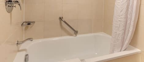 Un baño moderno con una bañera blanca, accesorios cromados y una cortina de ducha.