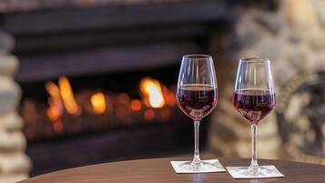Dos copas de vino sobre una mesa de madera, con una chimenea al fondo.