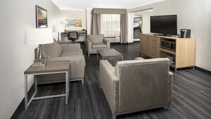A hotel room with a sofa, armchair, coffee table, desk, TV, and kitchenette. - Holiday Inn Greenville by IHG (Greenville)