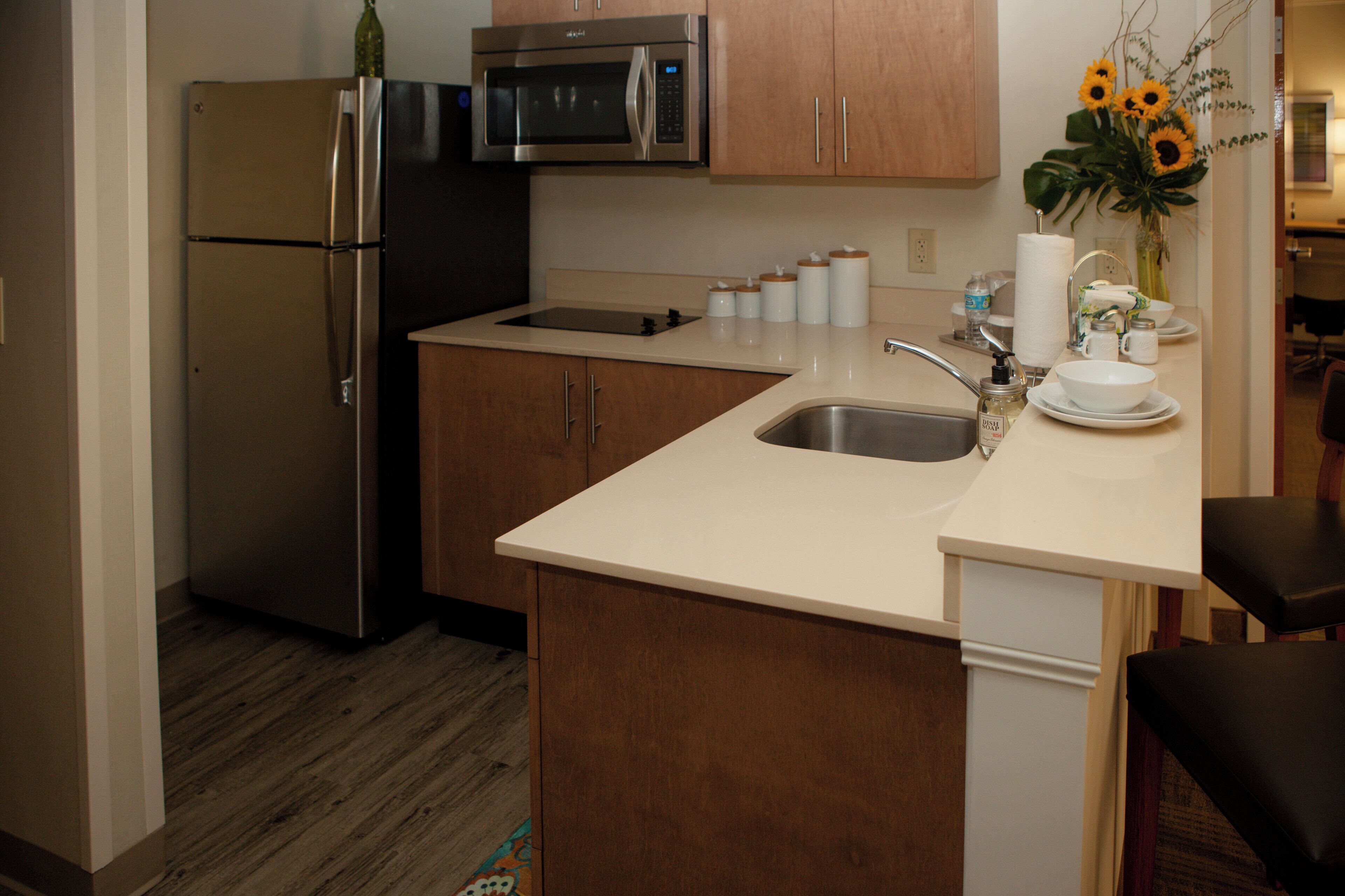 A compact kitchen with a refrigerator, microwave, sink, and wooden cabinets.