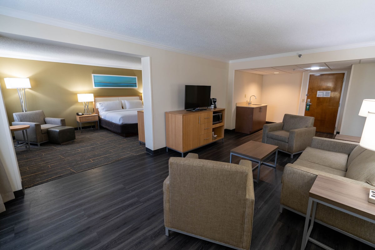 Ein Hotelzimmer mit Bett, Fernseher, Schreibtisch, Sessel und Sofa.
