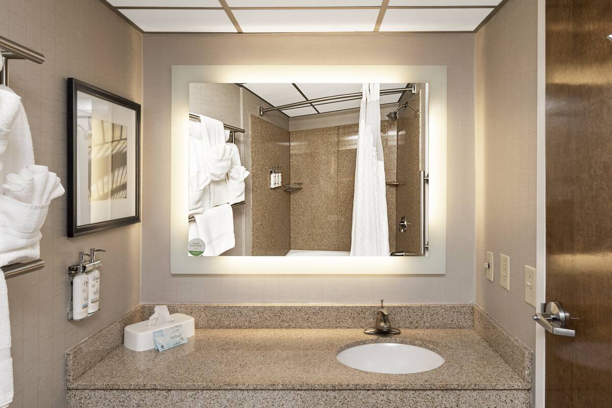 Ein modernes Badezimmer mit großem Spiegel, Waschbecken und Duschbereich.