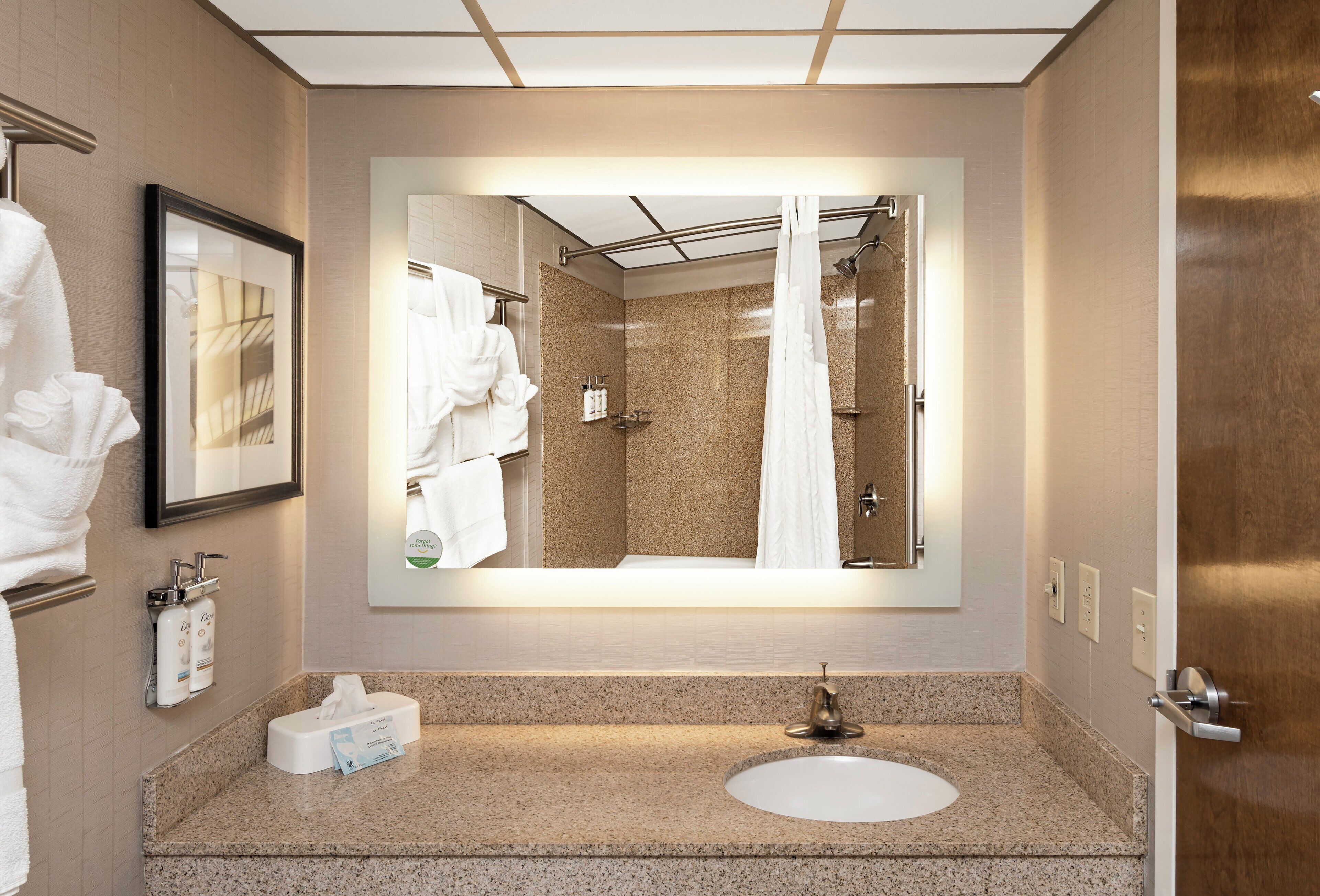 A modern bathroom with a large mirror, a sink, and a shower area.