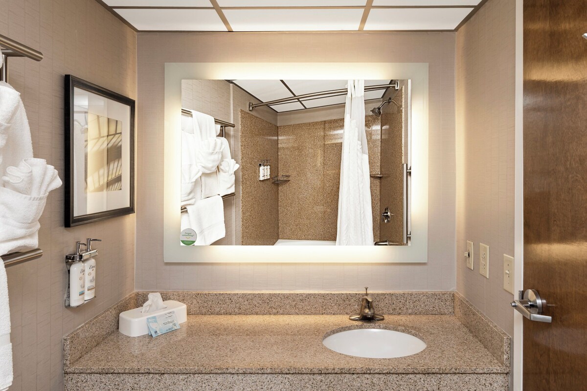 Un bagno moderno con uno specchio grande, un lavandino e una zona doccia.