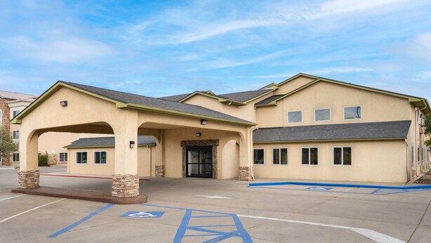 A hotel with a beige exterior, a covered entrance, and a parking lot with handicapped parking spaces.
