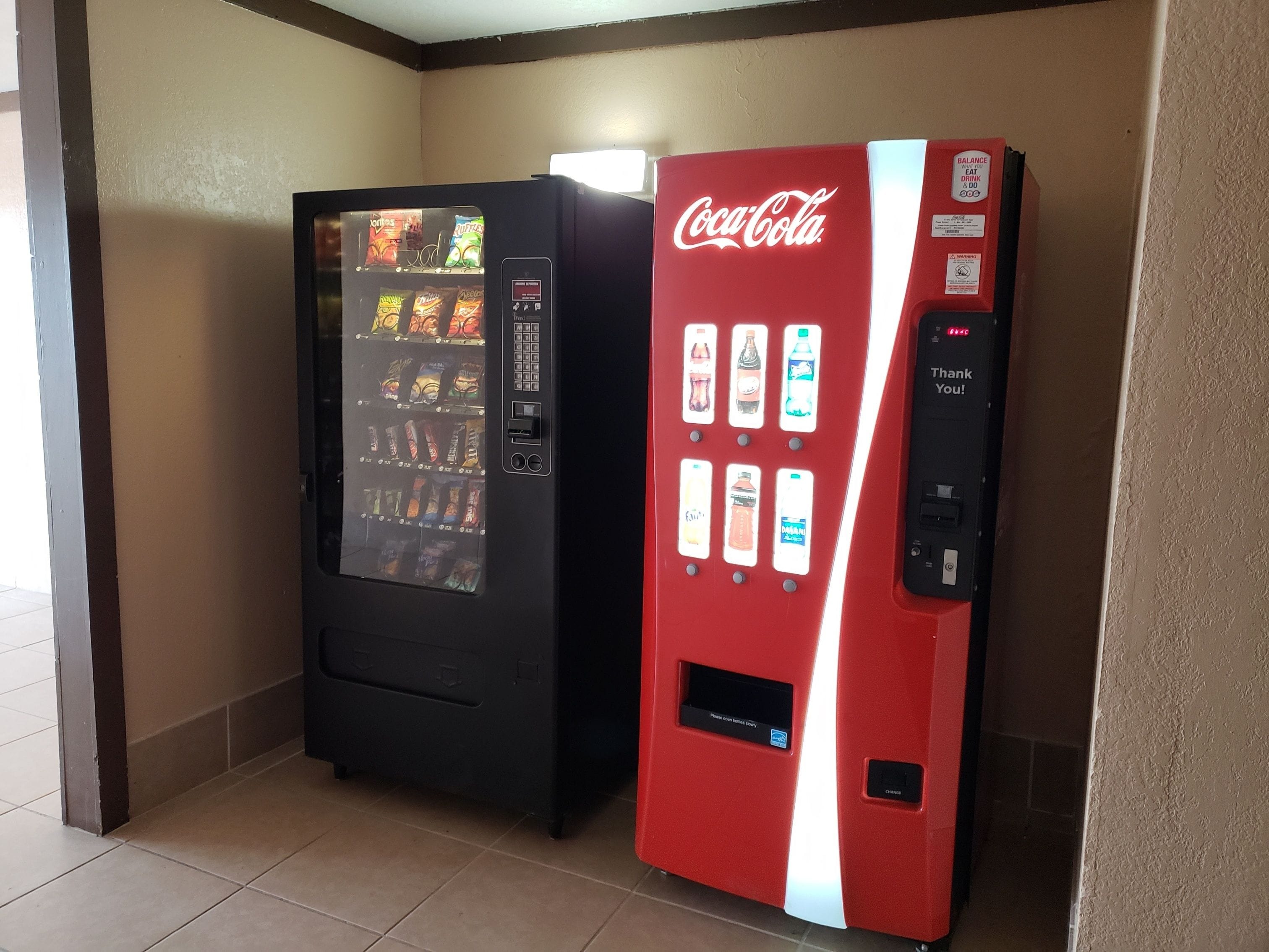 Two vending machines, one Coca-Cola branded and one with a variety of snacks.