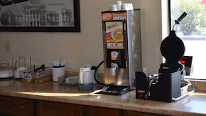A coffee machine, a coffee cup, and a menu on a counter. - Hill Country Inn & Suites (Copperas Cove)