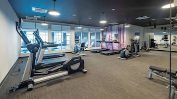 Un gimnasio con cintas de correr, elípticas y bancos de pesas.