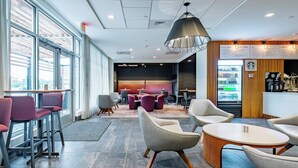 A modern lounge area with bar stools, round tables, and a seating area with armchairs.