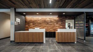 A reception area with two wooden reception desks, a wall with a wooden panel design, and a tiled floor.