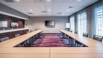 Una sala de conferencias con una larga mesa, sillas, un televisor y una pizarra.