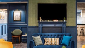 A modern living room with a blue sofa, yellow chairs, and a coffee table. - Ibis Paris Grands Boulevards Opera 9th (Paris)