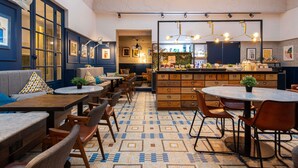A restaurant with a central bar area, multiple seating options including tables and chairs, and a patterned floor. - Ibis Paris Grands Boulevards Opera 9th (Paris)