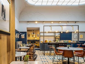 En restaurang med högt i tak, hängande lampor och ett mönstrat golv.