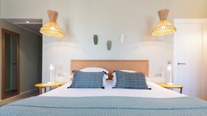 Habitación de hotel con una cama grande, dos mesitas de noche y dos lámparas colgantes.