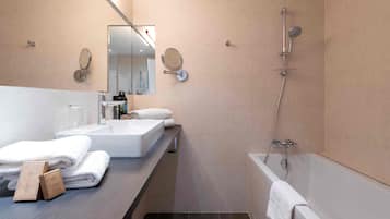 Un baño moderno con un espejo grande, una bañera y un tocador con lavabo y toallas.