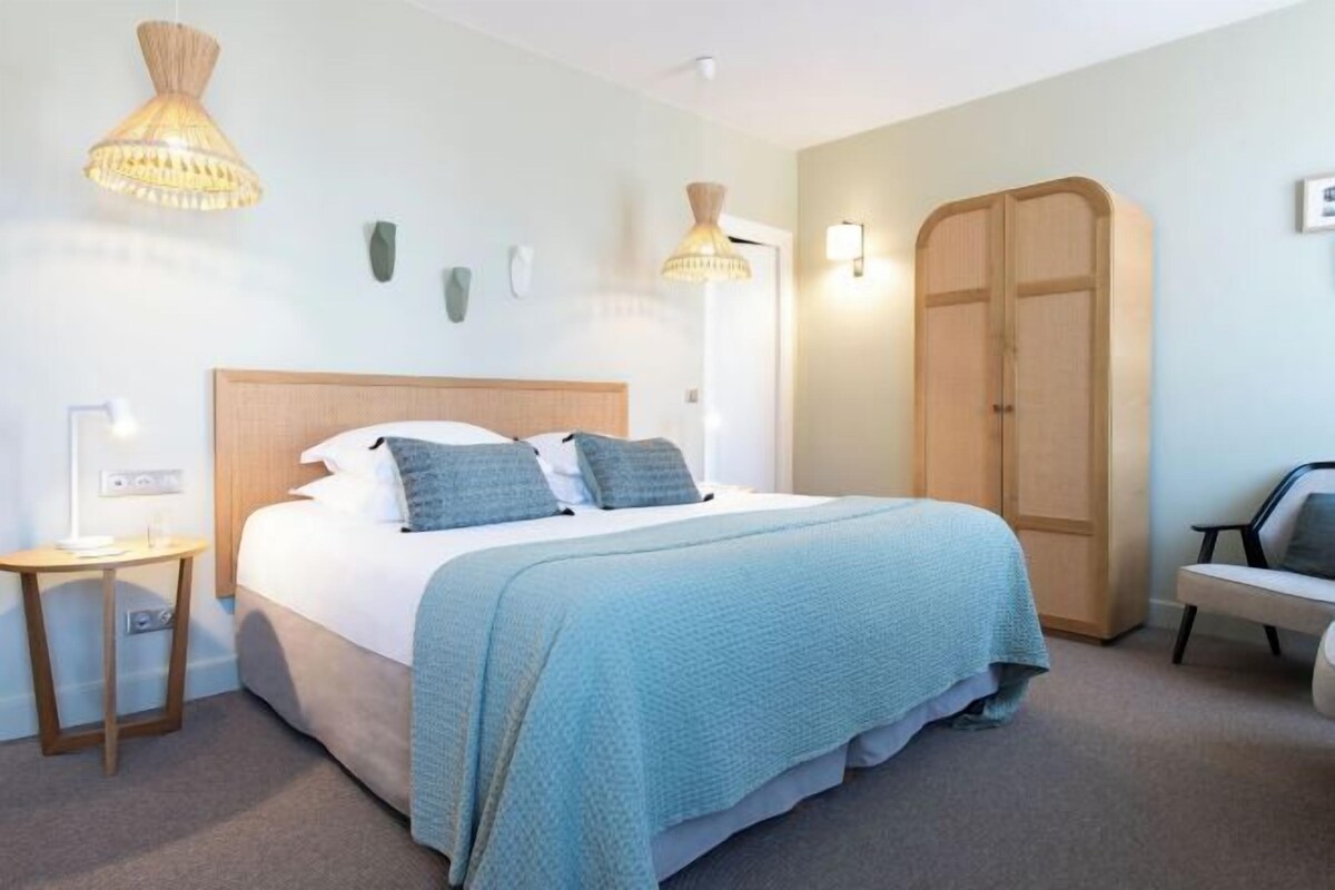 Une chambre d’hôtel avec un lit, des tables de chevet, une armoire et une chaise.
