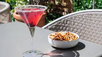 Una copa de martini con un borde salado y un cuenco de palitos de pretzel sobre una mesa.