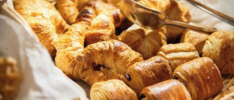 A basket filled with various types of pastries, including croissants and rolls.