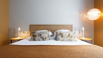 A neatly made bed with patterned pillows, a textured brown blanket, and two bedside tables with lamps.