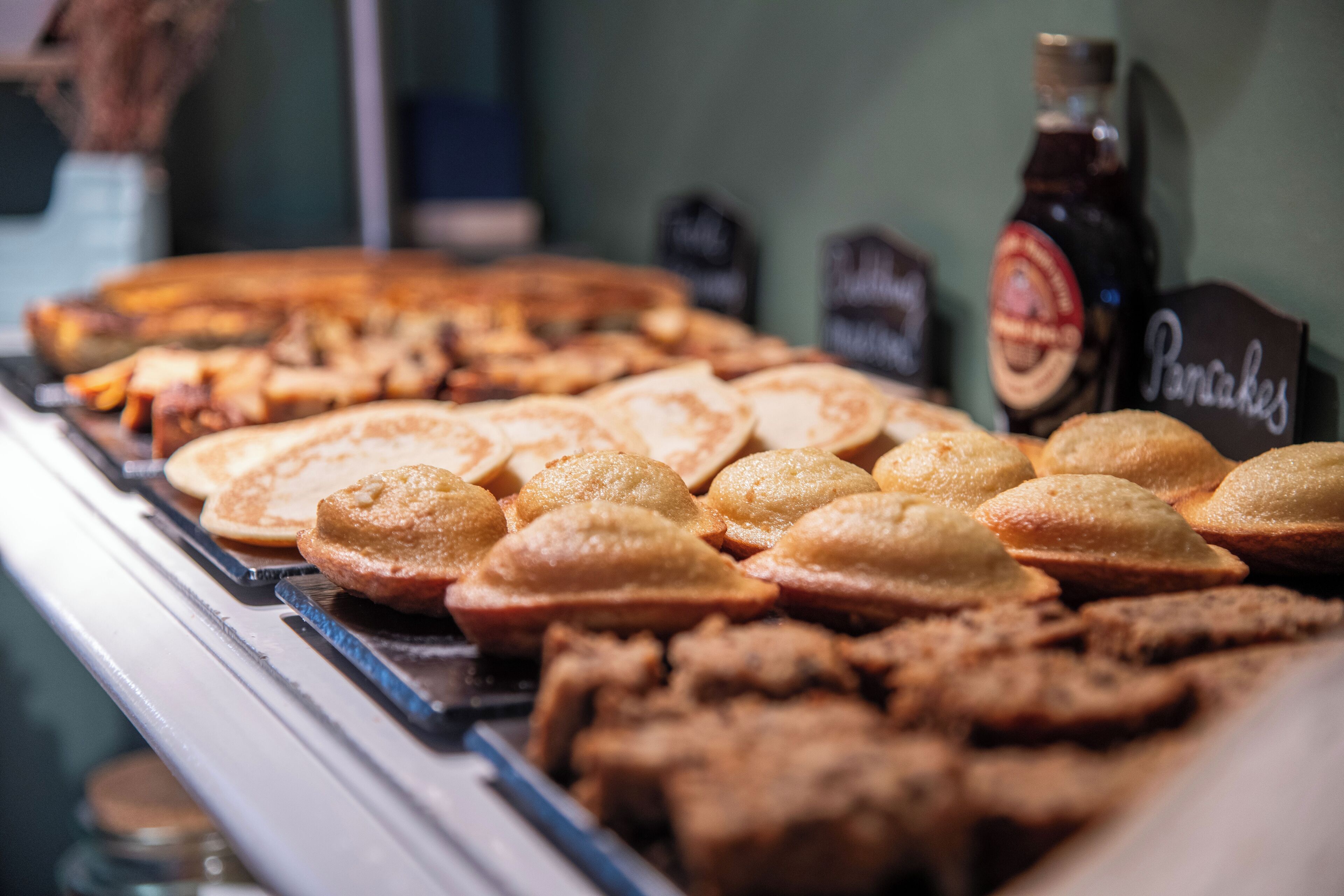 Een presentatie van diverse gebakken producten, zoals pannenkoeken en taarten, in een bakkerij.