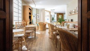 Una habitación amplia con piso de madera, muebles de mimbre y un gran ventanal que proporciona luz natural.