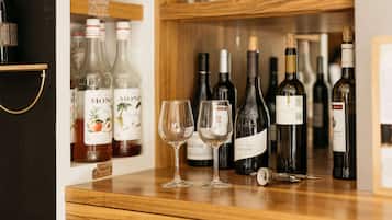 Una botellera con varias botellas y dos copas de vino vacías sobre una encimera de madera.
